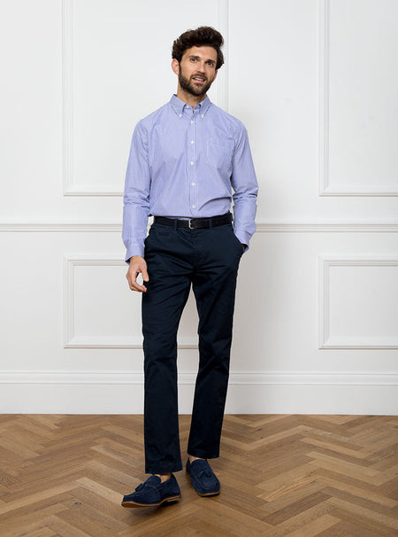 Man wearing long sleeved shirt with royal blue and white thin stripe made with 100% cotton from Thomas Mason.
